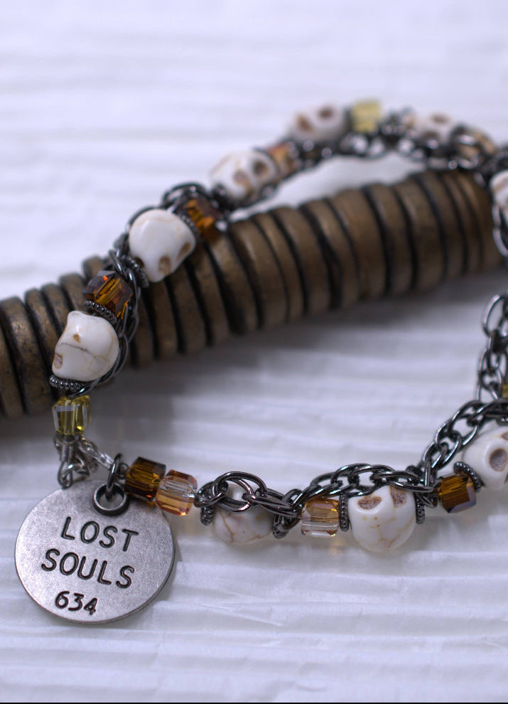 Bracelet with skull beads and 'Lost Souls 634' tag on a textured surface